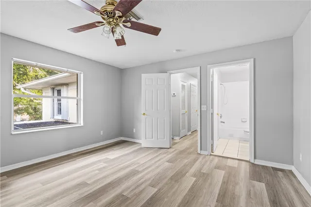 an empty room with a window and a ceiling fan