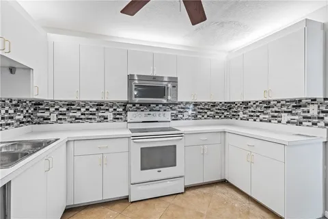 a kitchen with granite countertop white cabinets and white appliances