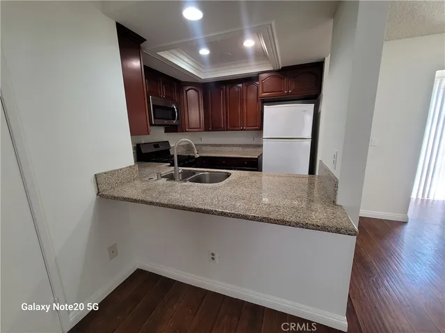 a kitchen with granite countertop a sink a refrigerator a microwave and cabinets