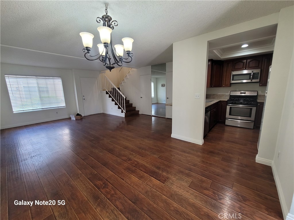 12235 Pine Street, Unit 18 Norwalk, CA 90650 - Photo 4 of 18 a view of a room with wooden floor staircase and a kitchen space