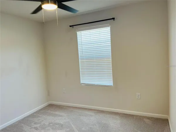 an empty room with a window and a fan