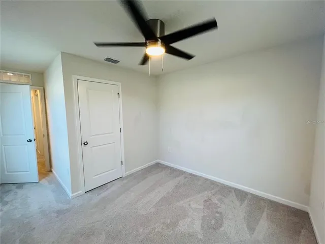 an empty room with ceiling fan and window