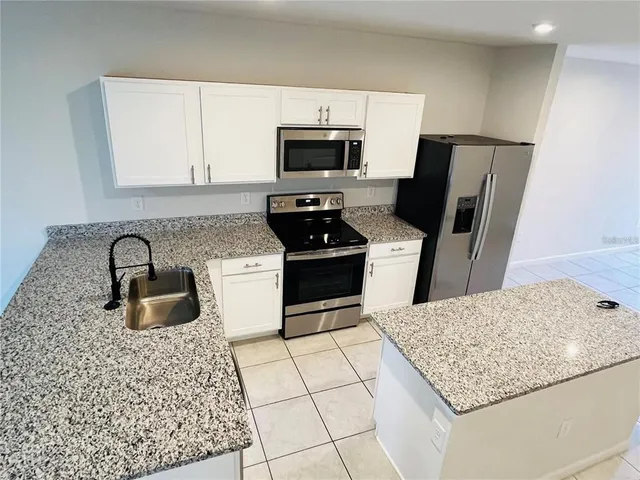 a kitchen with granite countertop a sink stove and refrigerator