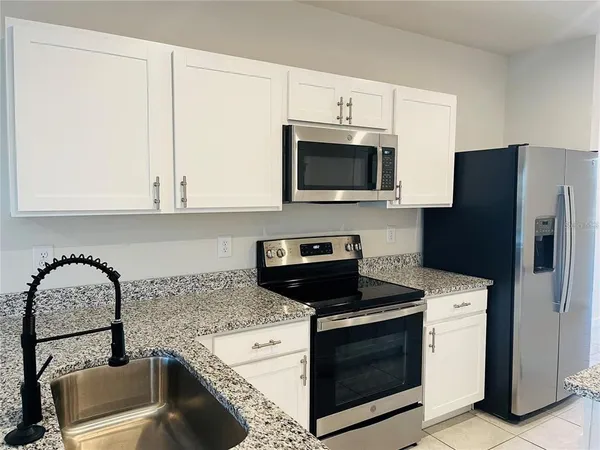 a kitchen with granite countertop white cabinets and stainless steel appliances