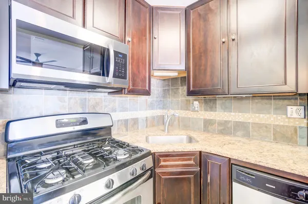 a kitchen with stainless steel appliances granite countertop a sink stove and cabinets