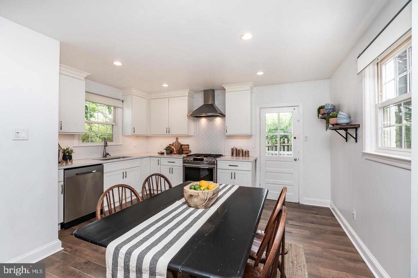 339 East Spring Avenue Ardmore, PA 19003 - Photo 13 of 44 a kitchen with stainless steel appliances granite countertop a stove a sink a refrigerator white cabinets and a dining table with wooden floor