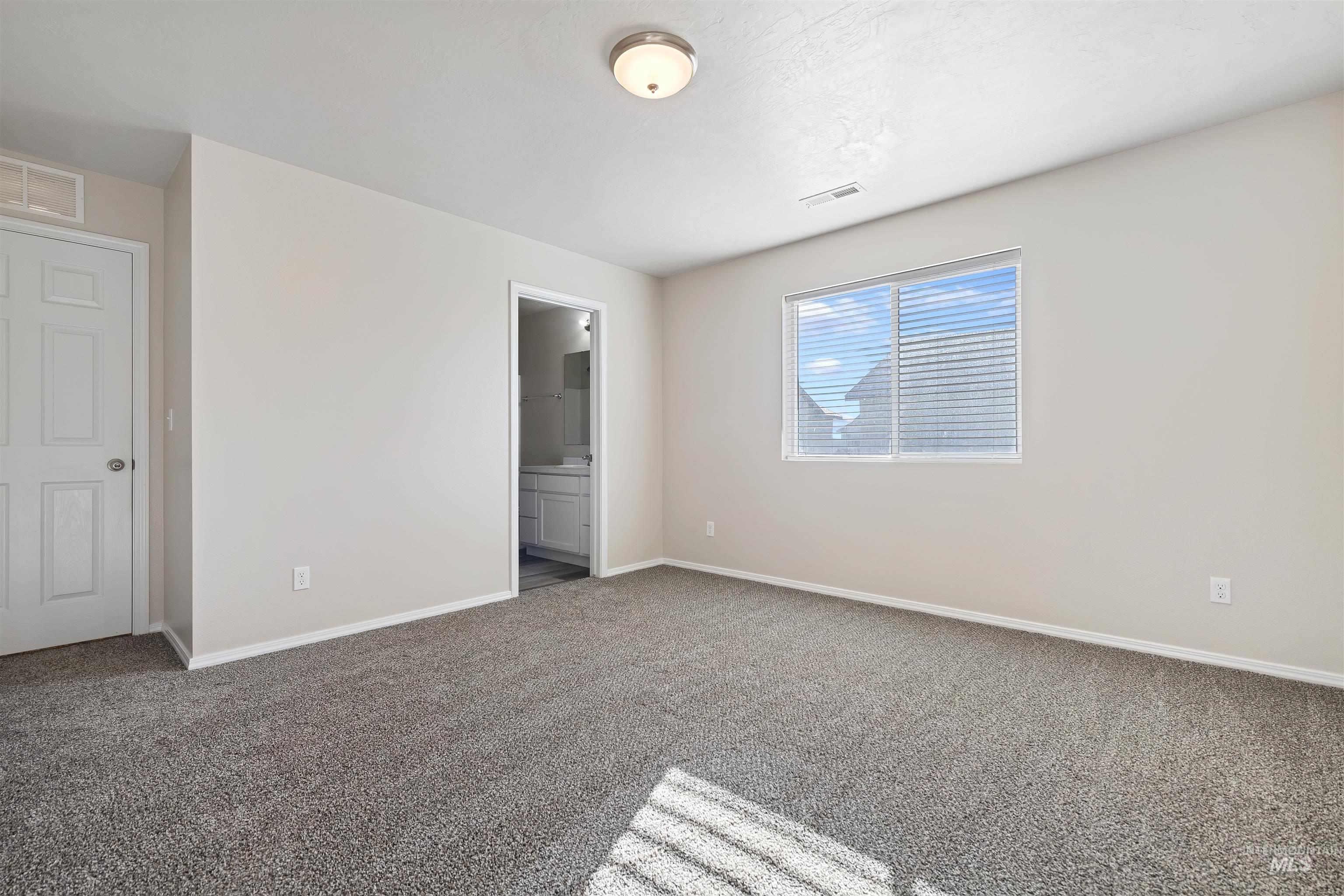 13559 Cocoa Beach Way Caldwell, ID 83607 - Photo 18 of 28 Unfurnished bedroom featuring connected bathroom and carpet flooring