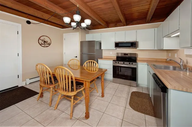 a kitchen with stainless steel appliances granite countertop a sink a stove a dining table and chairs with wooden floor