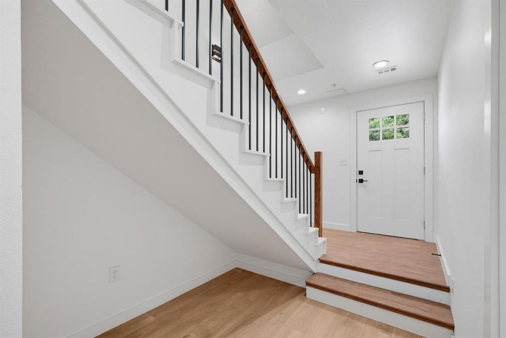 508 South O Connor Road Irving, TX 75060 - Photo 5 of 21 Foyer featuring wood-finish flooring, a white paneled entry door with multiple glass lites, and a staircase with a wood handrail and black metal balusters