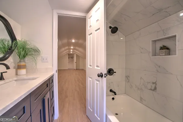 a bathroom with a granite countertop sink a mirror a bathtub and shower