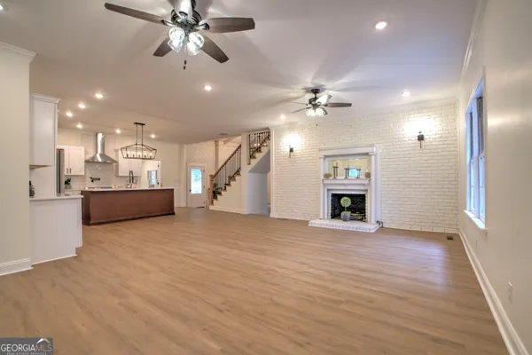 a view of an empty room with a fireplace and a chandelier fan