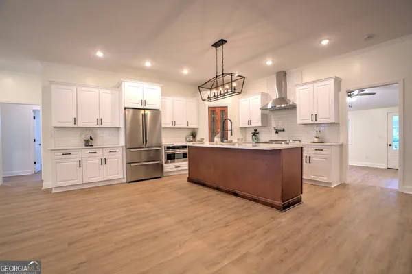 a large kitchen with stainless steel appliances kitchen island granite countertop a large counter top a sink cabinets and a refrigerator