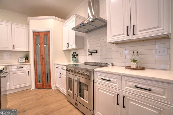 a kitchen with stainless steel appliances granite countertop a stove and white cabinets
