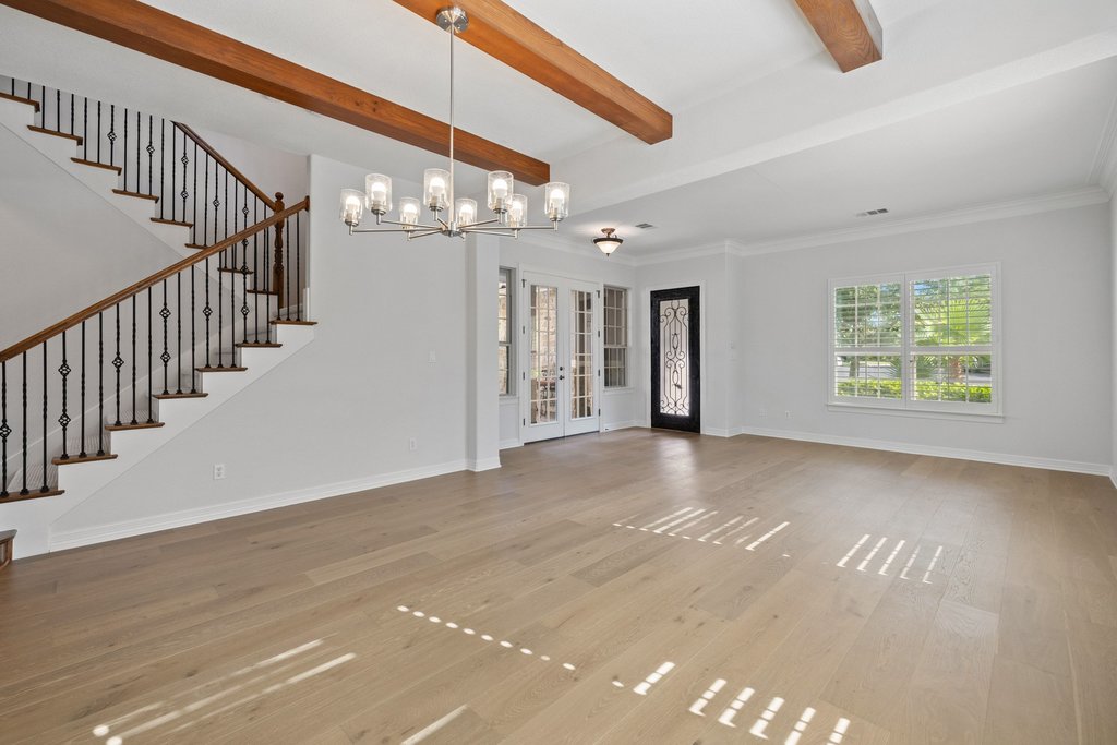 109 Largo Cove Austin, TX 78734 - Photo 17 of 40 Exposed wood beams frame a spacious living area, highlighted by light wood flooring and an ornate entry.