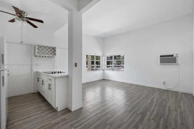 an empty room with wooden floor cabinet and a sink