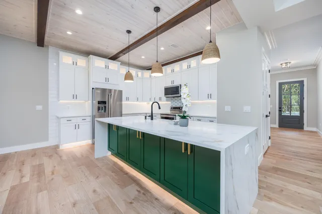 a large white kitchen with kitchen island a sink stainless steel appliances and cabinets