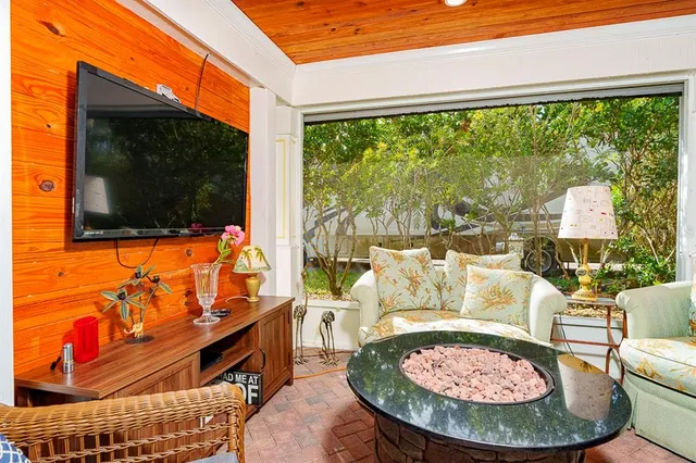 a living room with furniture a flat screen tv and floor to ceiling windows