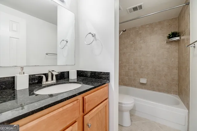 a bathroom with a granite countertop sink a toilet and shower