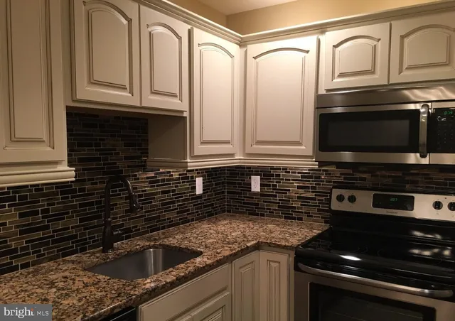 a kitchen with stainless steel appliances granite countertop a sink and a stove