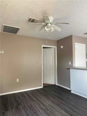 an empty room with wooden floor fan and windows
