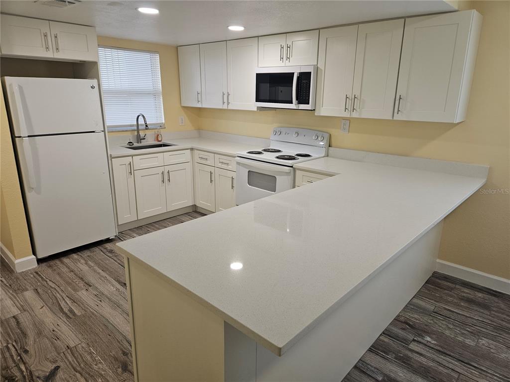 2045 Alpine Road, Unit 3 Clearwater, FL 33755 - Photo 11 of 18 a kitchen with stainless steel appliances a refrigerator sink and white cabinets