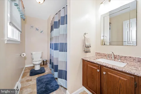 a bathroom with a granite countertop sink a toilet and a mirror
