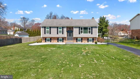 a view of house with a big yard and large trees