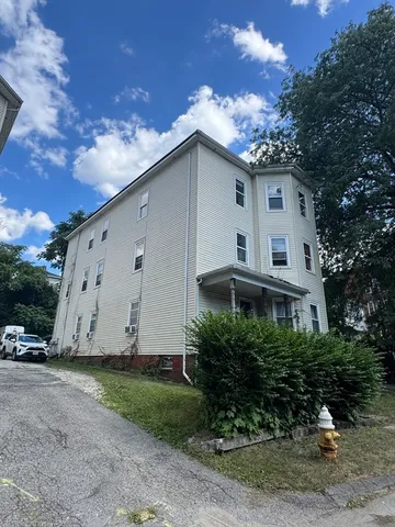 a view of a white house with a yard and large trees