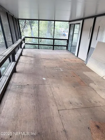 a view of an empty room with wooden floor and stairs