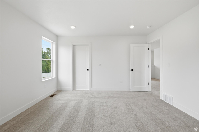 844 North 400 West Logan, UT 84321 - Photo 21 of 43 Spacious room featuring light gray carpet, white walls, two recessed ceiling lights, a white window with a green outdoor backdrop, and two white interior doors with black hardware