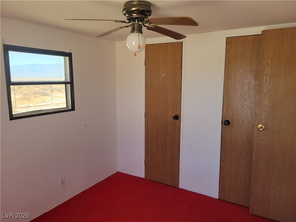 7950 South Wildhorse Road Pahrump, NV 89061 - Photo 19 of 28 Unfurnished bedroom with ceiling fan, two closets, and carpet floors