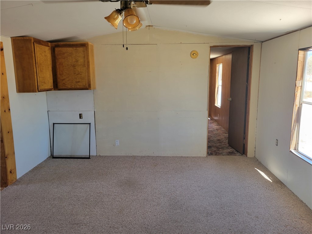 7950 South Wildhorse Road Pahrump, NV 89061 - Photo 28 of 28 Unfurnished living room with carpet flooring, lofted ceiling, and ceiling fan
