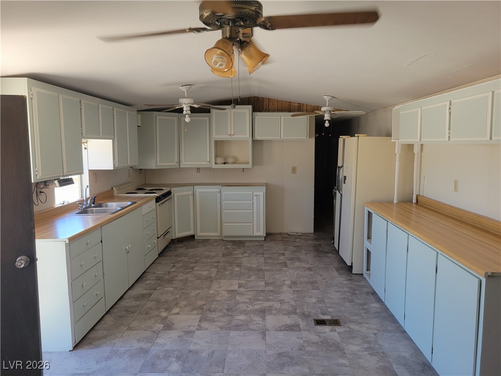7950 South Wildhorse Road Pahrump, NV 89061 - Photo 10 of 28 Kitchen featuring light countertops, white appliances, vaulted ceiling, white cabinetry, and open shelves