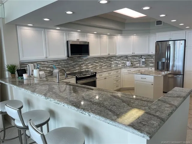 a kitchen with stainless steel appliances granite countertop a sink a stove a microwave a dining table and chairs