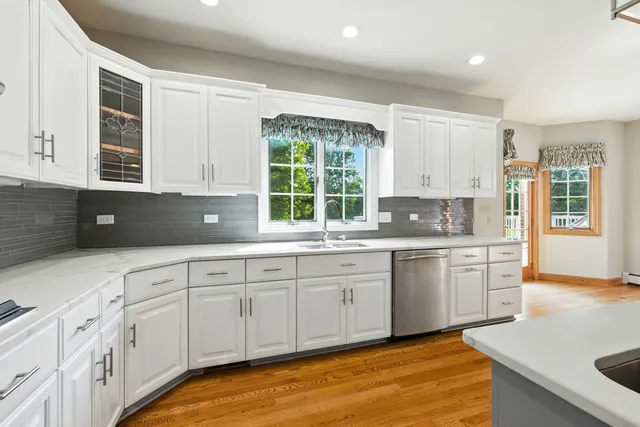 a kitchen with granite countertop white cabinets a sink a window and stainless steel appliances