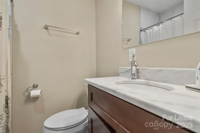a bathroom with a granite countertop sink a toilet and a mirror