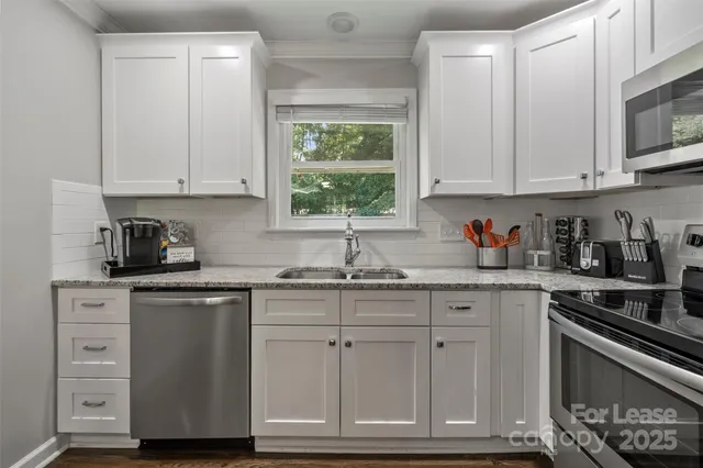 a kitchen with cabinets appliances a sink and a window