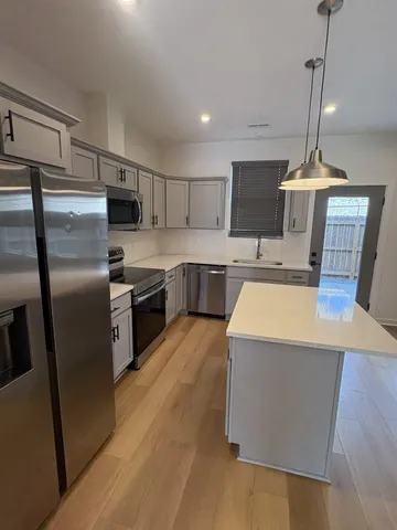 a kitchen with stainless steel appliances a stove a sink a refrigerator a center island a refrigerator and a stove