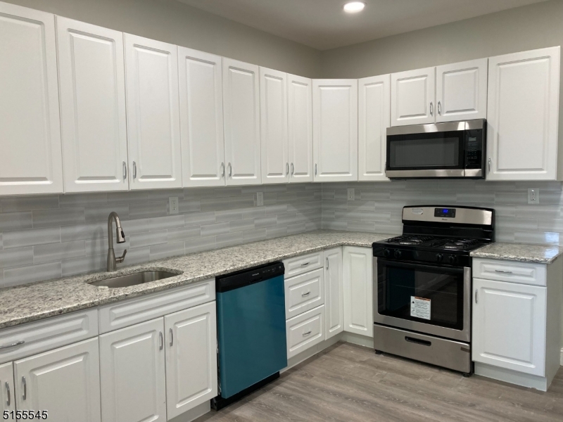 134 South 7th Street, Unit 2 Newark, NJ 07107 - Photo 4 of 13 a kitchen with stainless steel appliances granite countertop a stove a sink and white cabinets