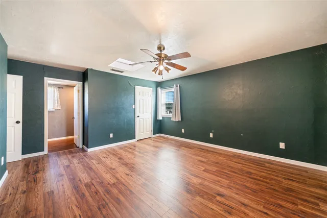 a view of a room with a ceiling fan window and wooden floor