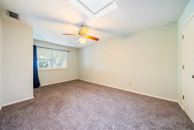 an empty room with windows and chandelier fan