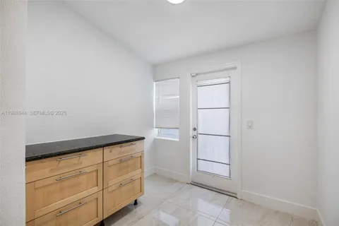 a kitchen with granite countertop a refrigerator and white cabinets
