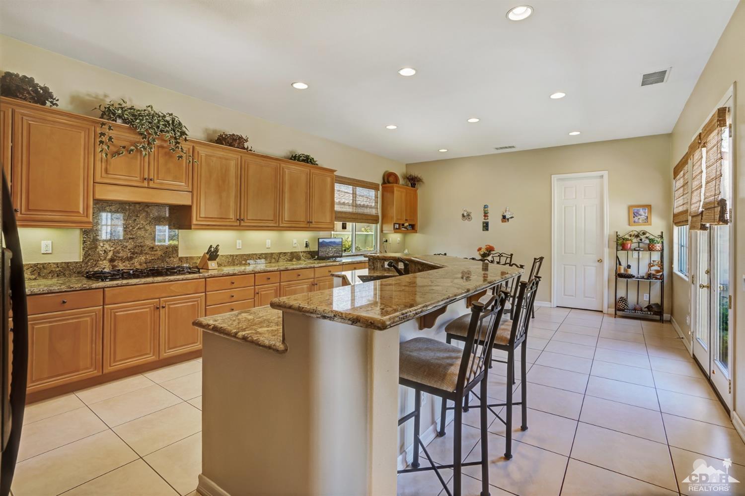 329 Loch Lomond Road Rancho Mirage, CA 92270 - Photo 14 of 50 a kitchen with stainless steel appliances kitchen island granite countertop a table and chairs