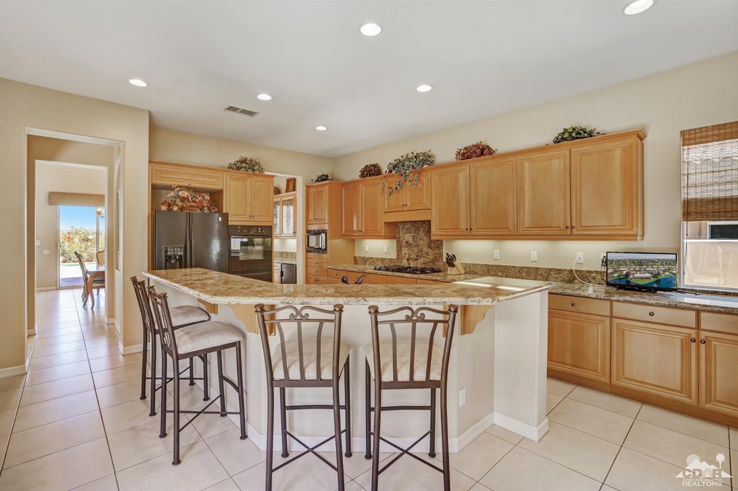 329 Loch Lomond Road Rancho Mirage, CA 92270 - Photo 15 of 50 a kitchen with a dining table chairs and white cabinets