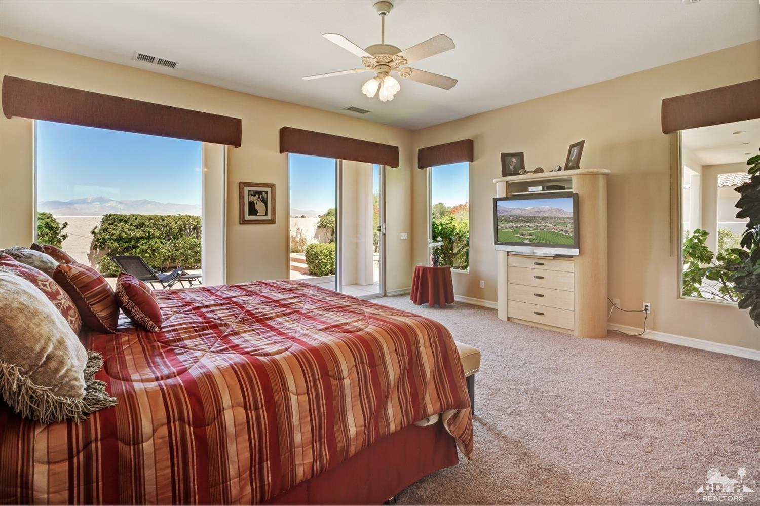 329 Loch Lomond Road Rancho Mirage, CA 92270 - Photo 23 of 50 a spacious bedroom with a bed a dresser and a chandelier