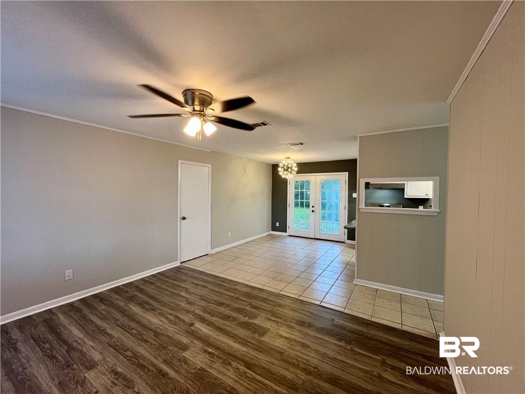 8636 Boe Road Irvington, AL 36544 - Photo 13 of 22 Unfurnished room featuring french doors, wood finished floors, a chandelier, ceiling fan, and crown molding