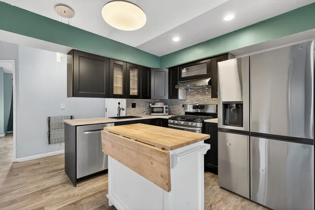 a kitchen with stainless steel appliances granite countertop a refrigerator stove top oven and sink