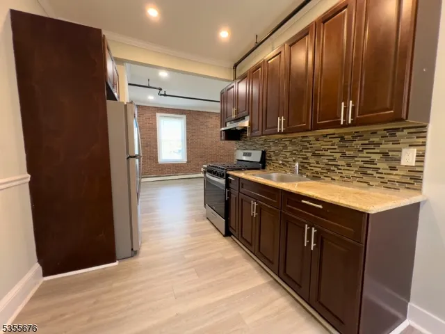 a kitchen with stainless steel appliances granite countertop a refrigerator a sink and wooden cabinets