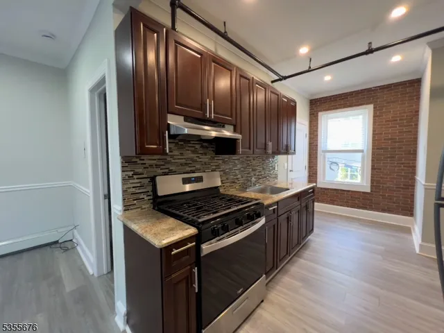 a kitchen with granite countertop wooden cabinets stainless steel appliances and a window