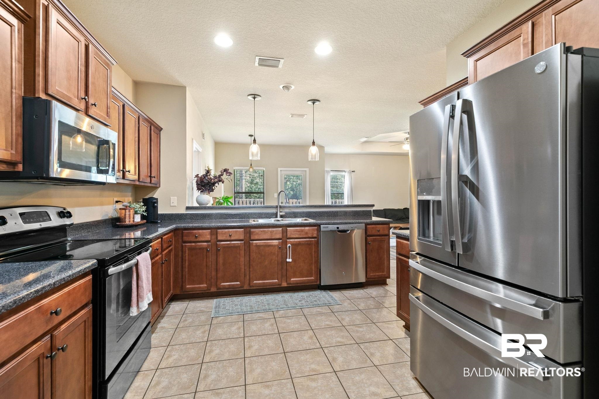 2216 Livingstone Court Mobile, AL 36695 - Photo 18 of 62 Kitchen featuring stainless steel appliances, wood cabinetry, dark countertops, and tile flooring